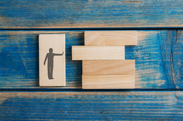 Silhouette of a man with a stop gesture pushing a wooden peg into a stack of them