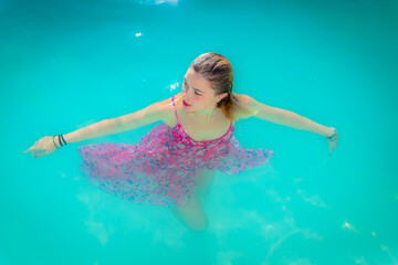 Jeune femme se baignant avec sa robe dans la piscine
