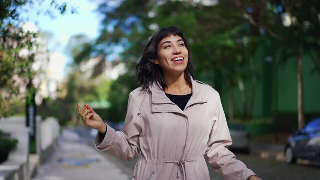 Carefree young woman celebrating life dancing and walking at the same time outside. Person walks in street feeling happy