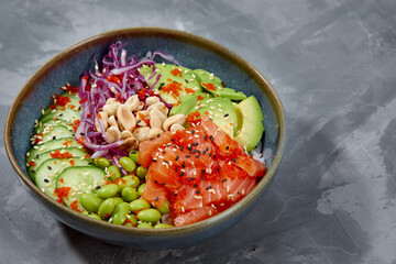 Top view on poke salad with salmon and green vegetable in the bowls on gray background. Copy space.