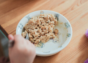a girl is eating oatmeal breakfast at the kitchen table