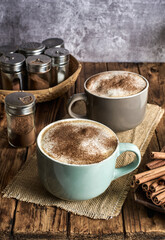 Two cups of Caffe Latte topped with cinnamon powder served in a cozy coffee shop.
