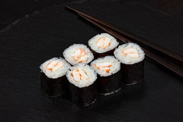 Traditional delicious freshsushi rolls with shrimp on a black background. Sushi roll with rice, cream cheese, avocado, salmon, sesame. Sushi menu. Japanese kitchen, restaurant