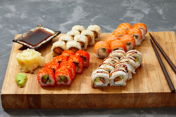 Different types of delicious and juicy sushi and rolls on a wooden board