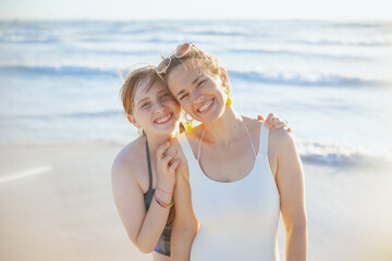 Portrait of happy stylish mother and teenage daughter at beach