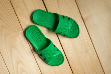 green slippers with hearts on a wooden table.