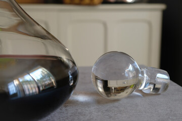 Decorative glass cork and carafe of red wine. The kitchen interior reflects in the glass. Selective focus.