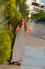 Young woman on the street with green not tall trees in sunny weather