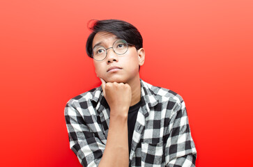 Thoughtful asian man thinking and wondering with hand touching skin as thinking gesture isolated...