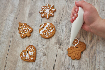Close up of drawing gingerbread Christmas snowflake sugar cookie on wooden table background with white icing