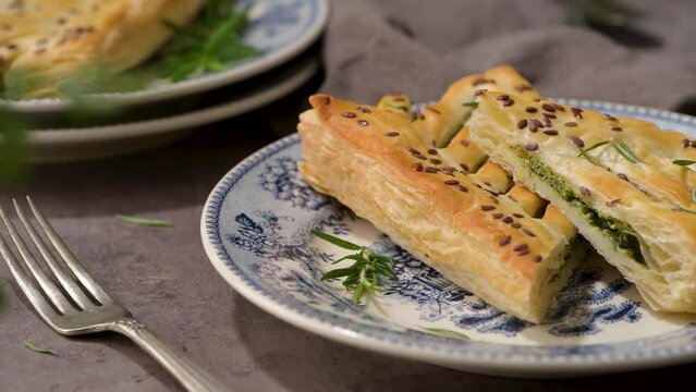 Typical portuguese snack with spinach. Spinach puff pastry with ricotta cheese, know as folhados de espinafres com queijo ricota on old fashioned ceramic plates.