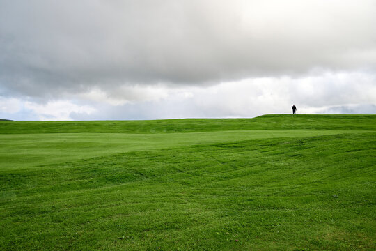 Unrecognizable traveler walking on green meadow
