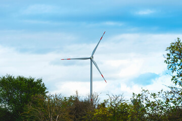 Fototapeta na wymiar Wind turbine generates green energy in a field at sunset