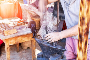 Blacksmith working on a horseshoe on top of an anvil in the open air