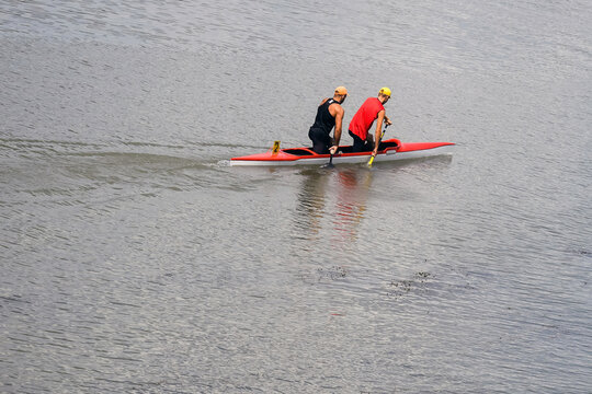 Two young athletes are sailing canoe on river, controlling oars. Active outdoor sports training. Copy space.