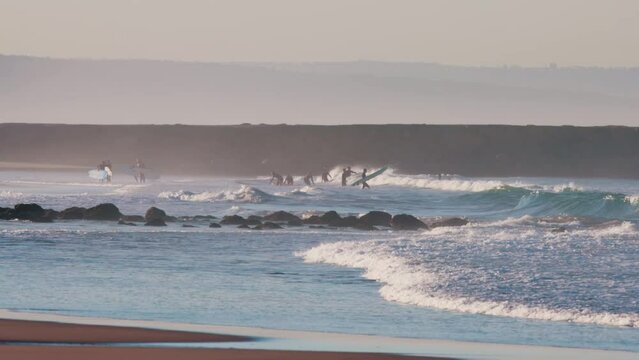 Serfers on a ocean wave at sunset, Atlantic Ocean - coast of Costa da Caparica, Portugal