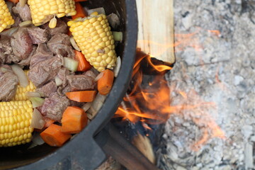 Cooking cauldron full of stew with corn, carrot and meat