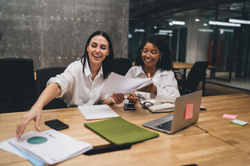 Cheerful diverse businesswomen with papers in office