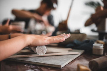 View of female hands works with clay makes future ceramic plate, ceramic artist makes classes of hand building in modern pottery workshop, creative people handcrafted design