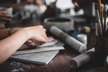 View of female hands works with clay makes future ceramic plate, ceramic artist makes classes of hand building in modern pottery workshop, creative people handcrafted design
