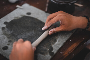 View of male hands works with clay makes future ceramic plate, ceramic artist makes classes of hand building in modern pottery workshop, creative people handcrafted design