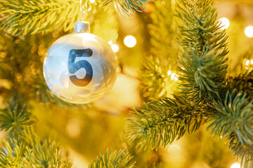 eine weiße Weihnachtskugel am Christbaum, mit einer Zahl (5) für den Adventskalender