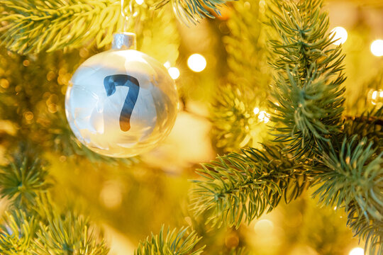 eine wei&szlig;e Weihnachtskugel am Christbaum, mit einer Zahl (7) f&uuml;r den Adventskalender