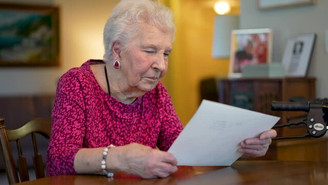 Elderly senior woman happy, sitting at table looking at photo memories.