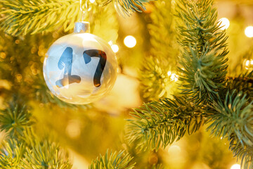 eine weiße Weihnachtskugel am Christbaum, mit einer Zahl (17) für den Adventskalender
