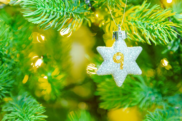 ein glitzernder Stern am Weihnachtsbaum mit einer Zahl (9) für einen Kalender