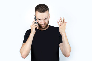 A young man with a short haircut and a short beard is talking on the phone and emotionally angry explaining to his business partners how to save money in a difficult time