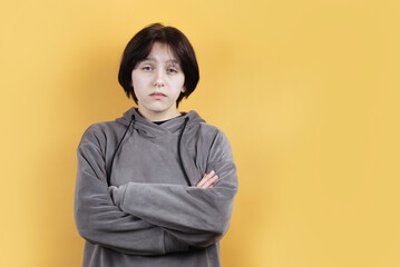 On a yellow background, a teenage girl looks suspiciously and mistrustfully at the camera, it is...