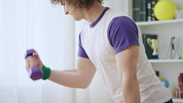Insane male sports freak training hard, doing dumbbell exercises home, 80s style