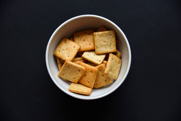 Delicious peppery cookies in a white plate on a black background.