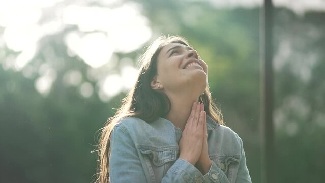 Grateful spiritual young woman thanking God praying to sky smiling. Happy free person looking at sky with HOPE and FAITH