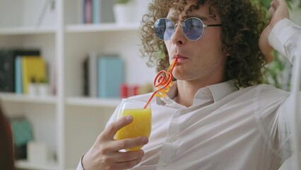 Funny curly man in sunglasses drinking cocktail, relax in office, lazy employee