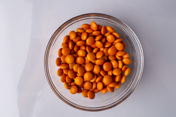 Orange candy coated chocolate button sprinkles in a bowl on bright marble - M&Ms, Smarties,...