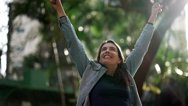 Happy person raises arm in the air in celebration. Woman celebrates success feeling CONFIDENT