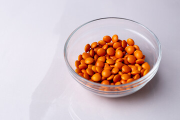 Orange candy coated chocolate button sprinkles in a bowl on bright marble - M&Ms, Smarties,...
