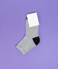 Grey kids socks on purple background. Socks with white label for your design. Mock up