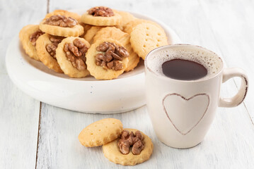 Various cookies in a bowl and a cup of coffee on a light table.