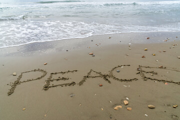 Words Written in the sand. The word PEACE written in the sand with the ocean in the background.
