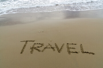 Words Written in the sand. The word TRAVEL written in the sand with the ocean in the background.