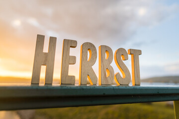 Herbst Schriftzug aus Holzbuchstaben im Wald mit verschiedenen Hintergründen.