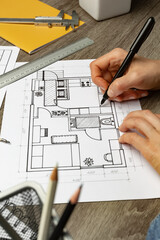 The designer draws a sketch of the interior on paper at the desktop. Blueprints.