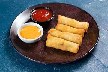Deep fried spring roll with tomato sauce and mayo dip served in dish isolated on table top view of fastfood