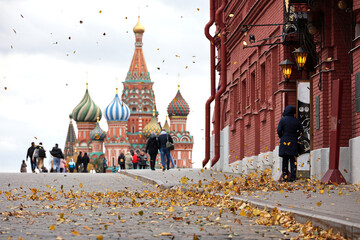 View to fallen leaves on a wind  and St. Basil's Cathedral on Red square. Tourists walking in autumn Moscow - obrazy, fototapety, plakaty