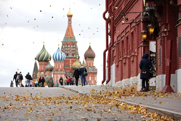 Poster Uitzicht op gevallen bladeren op een wind en St. Basil& 39 s Cathedral op het Rode plein. Toeristen die in de herfst Moskou lopen © Oleg