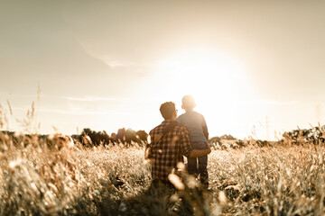 Father and son child relaxing together in a field at sunset 