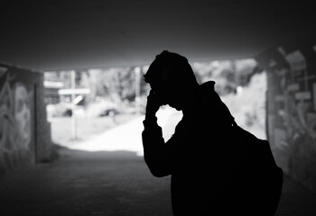 Tired sad man walking a dark city street tunnel 